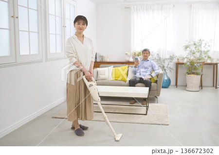 会話をしながら掃除機をかける笑顔の女性と60代の男性 会話をしながら掃除機をかける笑顔の女性と60代の男性 136672302