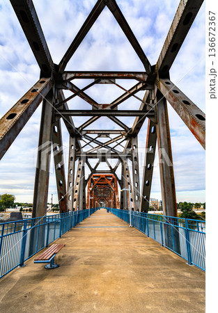 Clinton Presidential Park Bridge in Little Rock, Arkansas. Historic repurposed railway bridge features a rusty steel truss structure and blue railings over the Arkansas River Clinton Presidential Park Bridge in Little Rock, Arkansas. Historic repurposed railway bridge features a rusty steel truss structure and blue railings over the Arkansas River 136672367
