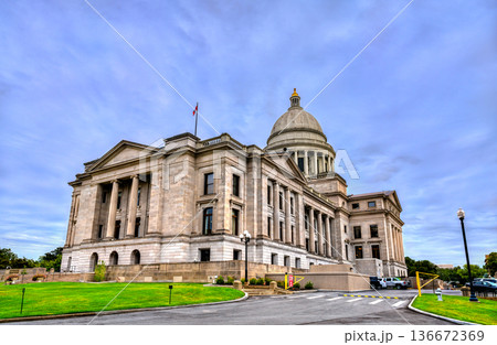 Arkansas State Capitol building in Little Rock. Historic Neoclassical government architecture features a limestone facade and dome under a blue sky with clouds 136672369