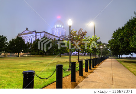 Oklahoma State Capitol building in Oklahoma City. Neoclassical government architecture features an illuminated dome obscured by heavy fog and a walkway with black bollards at night Oklahoma State Capitol building in Oklahoma City. Neoclassical government architecture features an illuminated dome obscured by heavy fog and a walkway with black bollards at night 136672371