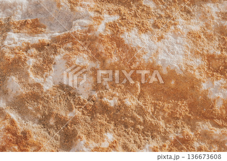 Close-up of natural stone texture with coral and ginger orange tones. Rough rocky surface pattern 136673608