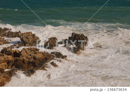 Sea foam crashing against rocky shore. Sea foam crashing against rocky shore. 136673634
