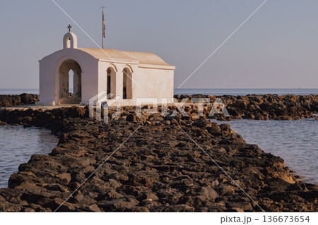 Picturesque seclusion: the whitewashed chapel on a narrow rock jetty extending into the Aegean 136673654