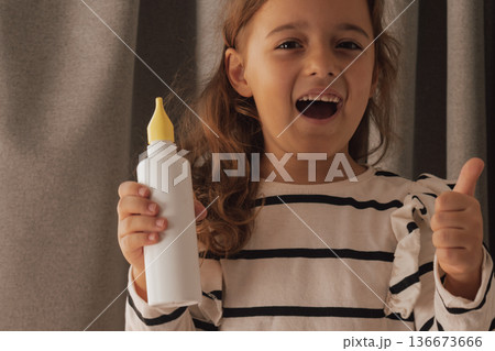 Smiling while using a nasal spray and giving a confident thumbs up sign 136673666