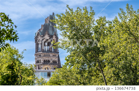Berlin, germany, august 14,2023. Kaiser wilhelm memorial church tower, known as a berlin landmark and symbol of peace, rising above green trees on a sunny day Berlin, germany, august 14,2023. Kaiser wilhelm memorial church tower, known as a berlin landmark and symbol of peace, rising above green trees on a sunny day 136674738