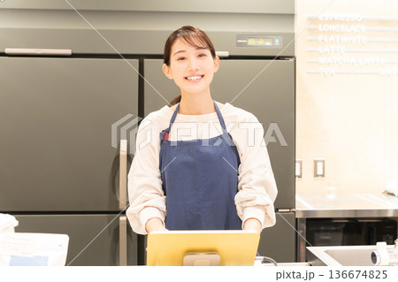 レジ前で案内をする若い女性店員 136674825