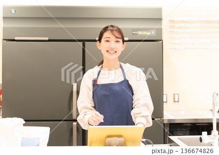 レジ前で案内をする若い女性店員 136674826