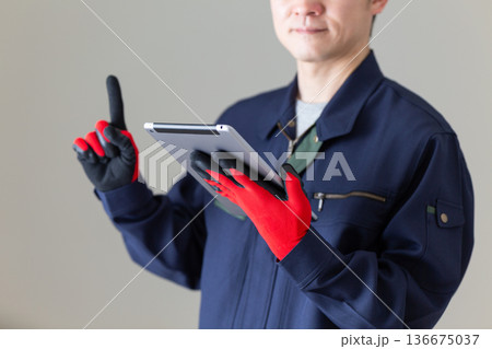 タブレットを持って人差し指を立てる作業服のミドル男性ビジネスマン 136675037
