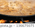 Traditional Spanish paella cooking in pan over open fire close-up 136675075