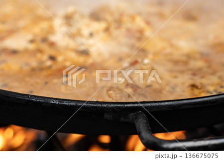 Traditional Spanish paella cooking in pan over open fire close-up Traditional Spanish paella cooking in pan over open fire close-up 136675075