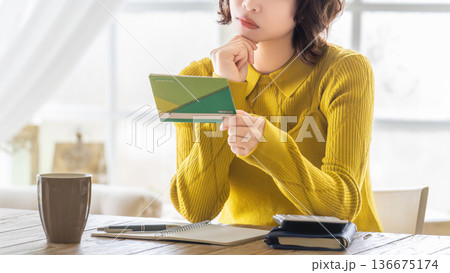 通帳を見て考える女性 136675174
