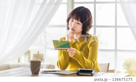 通帳を見て考える女性 通帳を見て考える女性 136675175