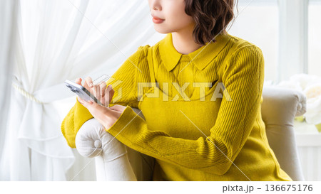 ソファに座ってスマートフォンを使う女性 ソファに座ってスマートフォンを使う女性 136675176