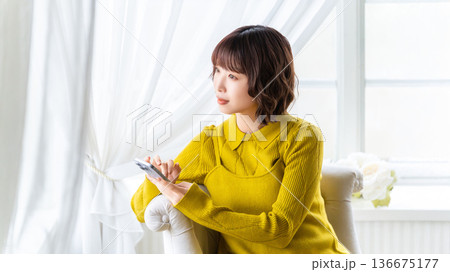 ソファに座ってスマートフォンを使う女性 ソファに座ってスマートフォンを使う女性 136675177