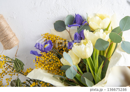 Spring bouquet of flowers. Irises, tulips, mimosa and eucalyptus. Yellow and blue flower. Bud close-up. Floral background. Purple iris, white double tulip. March mood. Spring bouquet of flowers. Irises, tulips, mimosa and eucalyptus. Yellow and blue flower. Bud close-up. Floral background. Purple iris, white double tulip. March mood. 136675286