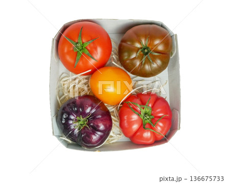 Top view of colorful heirloom tomatoes in a box. Fresh organic farm produce, healthy food, vegan nutrition and gourmet cooking concept isolated on white background Top view of colorful heirloom tomatoes in a box. Fresh organic farm produce, healthy food, vegan nutrition and gourmet cooking concept isolated on white background 136675733