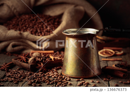 Turkish copper coffee pot with a bag of roasted coffee beans and spices. 136676373