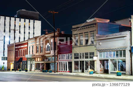 Historic storefronts on North State Street in Jackson, Mississippi. A row of vintage commercial buildings with colorful brick facades and decorative cornices is illuminated by streetlights at night 136677129