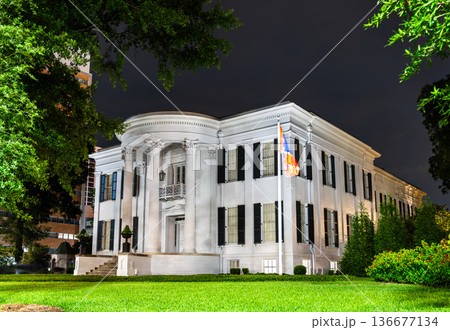 Mississippi Governor's Mansion in Jackson. Historic Greek Revival architecture features a semi-circular portico with Corinthian columns and black shutters illuminated at night 136677134