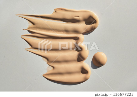 Liquid foundation cosmetic product showing textured smears and drop 136677223