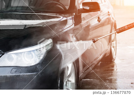 A man washes his car at a self service car wash. The car is washed using high pressure water. Self-service car wash. 136677870