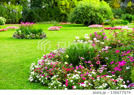 Beautiful landscaped garden with colorful flower beds and green lawn Beautiful landscaped garden with colorful flower beds and green lawn 136677874