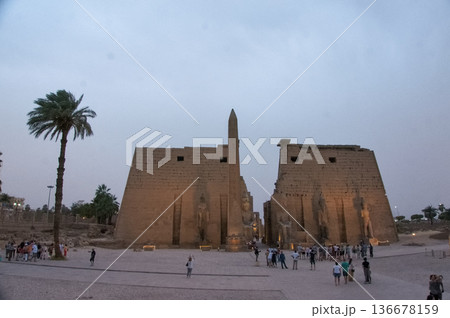 エジプト、ルクソール神殿の第一塔門。ライトアップされたオベリスクとラムセス2世の巨像 136678159