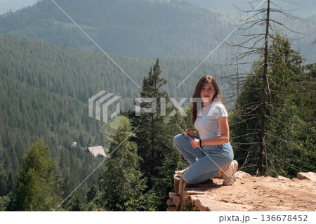 Young woman relaxing on mountain viewpoint in summer forest 136678452
