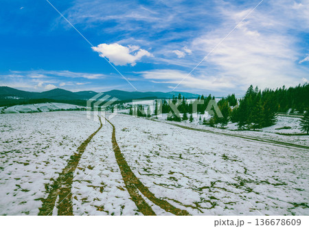 Traces of the car on a snow-covered field. Mountain landscape in winter 136678609