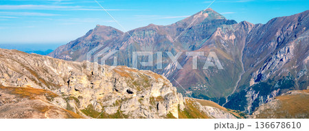 Mountain ridge with blue cloudy sky. Mountain landscape with day sky and clouds. Grossglockner High Alpine Road. Austria Mountain ridge with blue cloudy sky. Mountain landscape with day sky and clouds. Grossglockner High Alpine Road. Austria 136678610