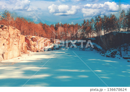 Winter nature. Frozen lake with a rocky shore. Granite quarry on a sunny day 136678624