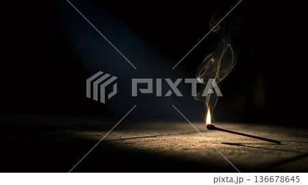 Single burning matchstick lighting dark background with smoke 136678645