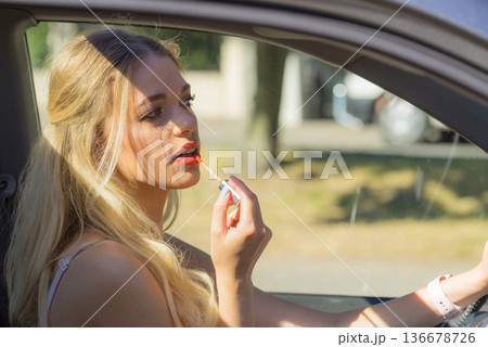 Woman applying lip gloss in car Woman applying lip gloss in car 136678726