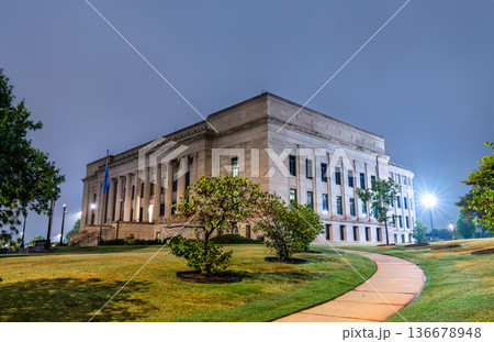 Historic Oklahoma Judicial Center building stands on the State Capitol grounds in Oklahoma City. The Neoclassical structure features a limestone facade with columns illuminated at night. 136678948