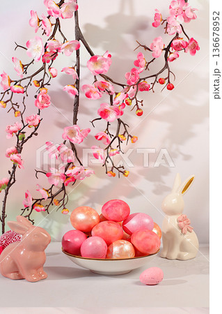 Abstract Easter composition with decorated eggs on an elegant kitchen table surrounded by spring cherry blossoms and bunnies. Happy Easter concept. Banner and beautiful greeting card 136678952