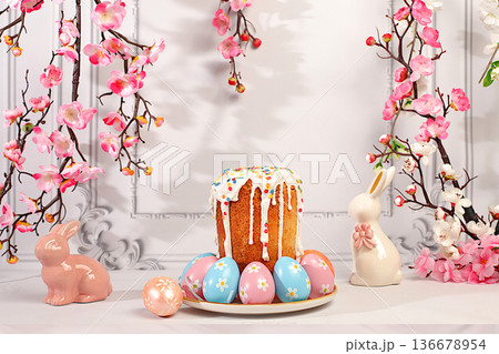 Abstract Easter composition featuring a traditional Russian meringue kulich and decorated eggs on an elegant kitchen table with spring cherry blossoms.Happy Easter concept. Screen banner 136678954