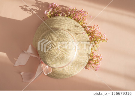 Straw Hat with Pink Ribbon and Flowers. Romantic Spring Summer Flatlay on Peach Background 136679316