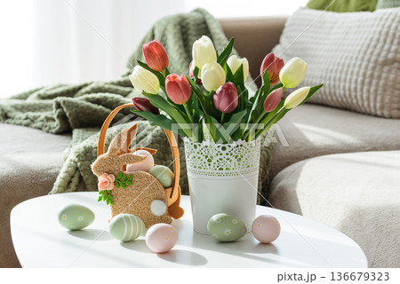 Easter Bunny Basket with Decorated Eggs and Tulip Bouquet. Cozy Spring Arrangement Easter Bunny Basket with Decorated Eggs and Tulip Bouquet. Cozy Spring Arrangement 136679323