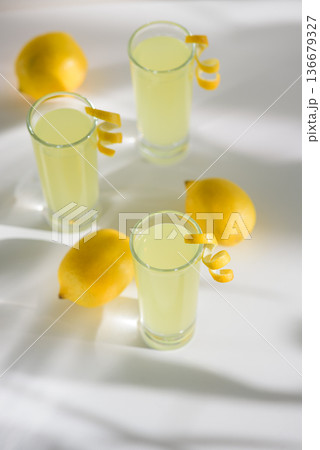 Limoncello Glasses with Curled Lemon Peels and Fresh Lemons. Refreshing Summer Italian Beverage Limoncello Glasses with Curled Lemon Peels and Fresh Lemons. Refreshing Summer Italian Beverage 136679327