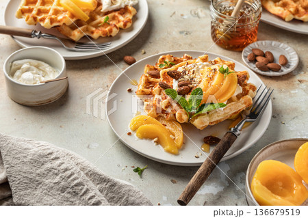 Belgian waffles with cream, honey, canned apricots and almonds, served for breakfast 136679519