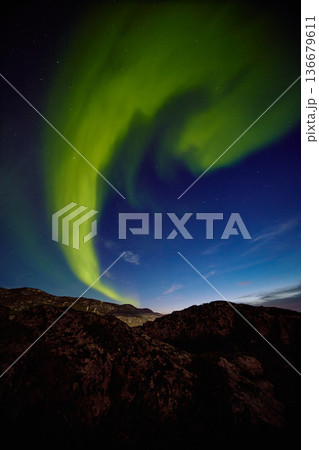 Aurora borealis over ocean in Teriberka, Russia, Murmansk region, Northern lights, Starry sky with polar lights and clouds. Night autumn landscape with bright aurora, stars, sea 136679611