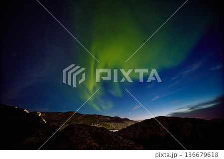 Aurora borealis over ocean in Teriberka, Russia, Murmansk region, Northern lights, Starry sky with polar lights and clouds. Night autumn landscape with bright aurora, stars, sea 136679618