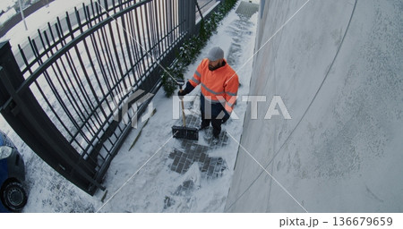City Maintenance Worker Shovels Snow From Icy Pathway Next to Residential or Commercial Building City Maintenance Worker Shovels Snow From Icy Pathway Next to Residential or Commercial Building 136679659