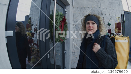 Courier With Large Delivery Backpack Arrives at House and Rings Doorbell 136679690