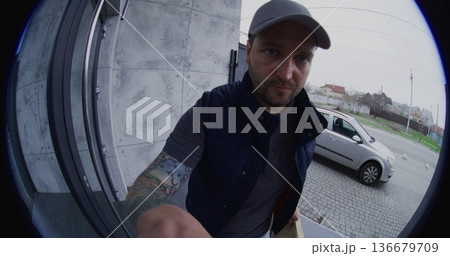Male Courier Ringing Bell and Leaving an Order at Door 136679709