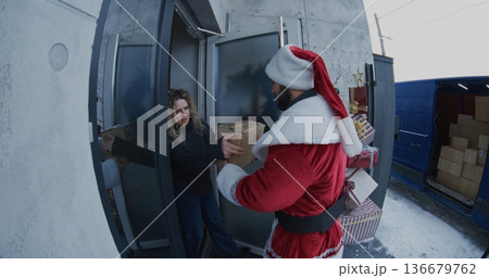 Santa Claus Delivers Package to Woman at Doorstep Santa Claus Delivers Package to Woman at Doorstep 136679762