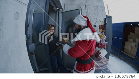 Santa Claus Delivers Package to Woman at Doorstep 136679764