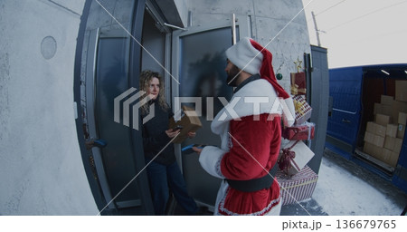 Santa Claus Delivers Package to Woman at Doorstep Santa Claus Delivers Package to Woman at Doorstep 136679765