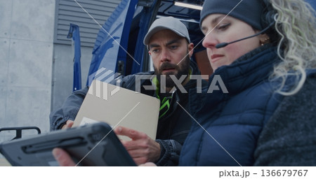 Man Stacks Boxes Inside Vehicle While Woman Wearing Headset Scans Packages 136679767