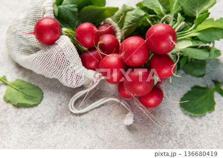 Fresh organic radishes spilling from a reusable mesh bag Fresh organic radishes spilling from a reusable mesh bag 136680419